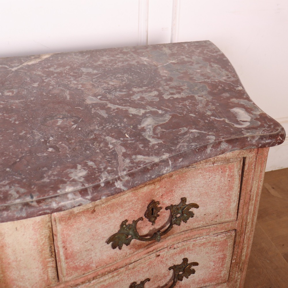 A Louis XV style French painted commode featuring a serpentine front, grey marble top, four drawers with rococo brass handles, and a distressed pale pink painted finish. View VIII