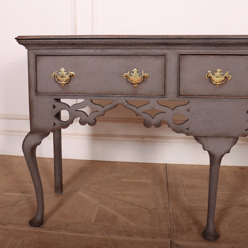 A grey-painted antique dresser base featuring three drawers with brass handles, a decorative pierced fretwork apron, and cabriole legs. View II