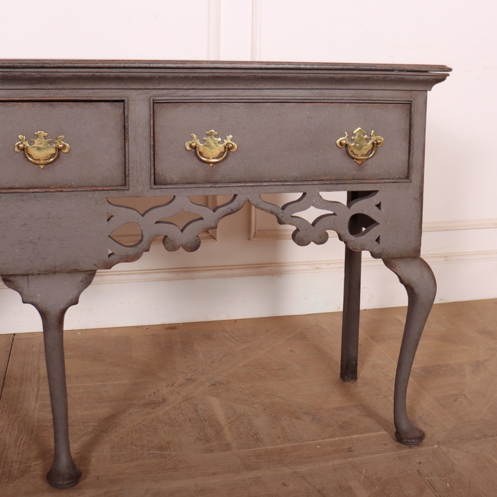 A grey-painted antique dresser base featuring three drawers with brass handles, a decorative pierced fretwork apron, and cabriole legs. View IV