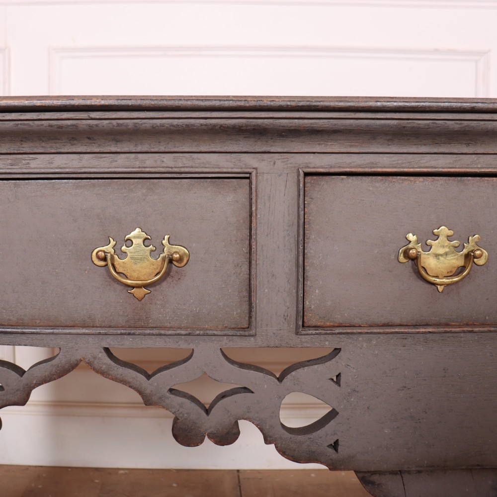 A grey-painted antique dresser base featuring three drawers with brass handles, a decorative pierced fretwork apron, and cabriole legs. View V