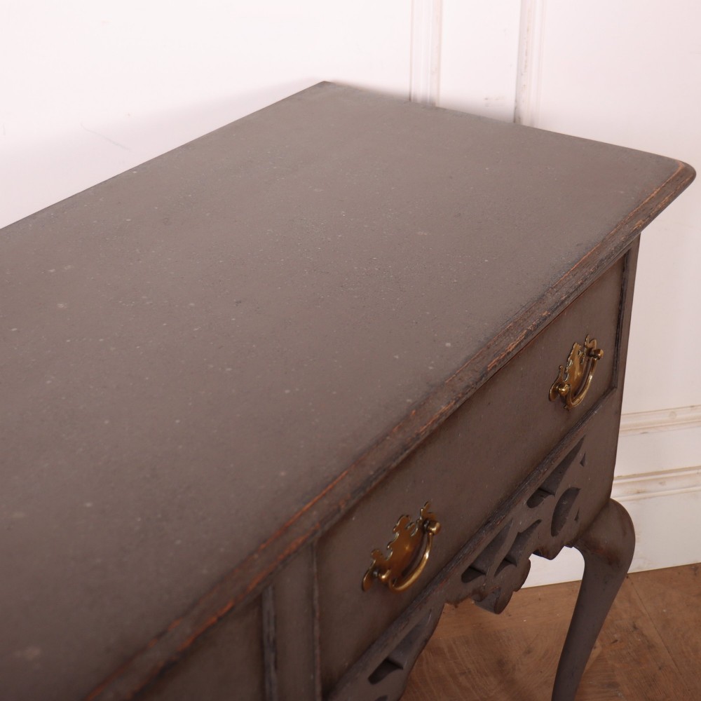 A grey-painted antique dresser base featuring three drawers with brass handles, a decorative pierced fretwork apron, and cabriole legs. View X