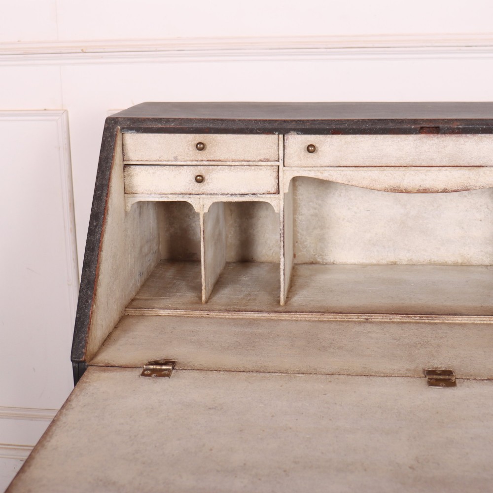 A small painted English bureau secretaire featuring a dark grey exterior, three lower drawers with brass handles, and a drop-front slant lid opening to a cream fitted interior with pigeonholes. View IV