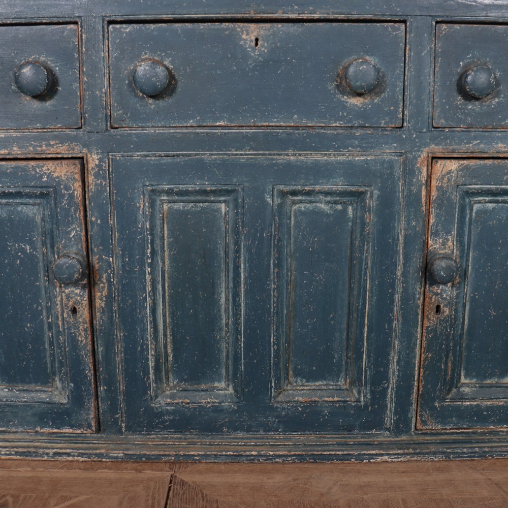 A large two-part dark blue painted timber dresser featuring a glazed upper display section with grid-paned doors and a dentil corniced top, resting on a base with three drawers and three panelled cupboard doors. View V