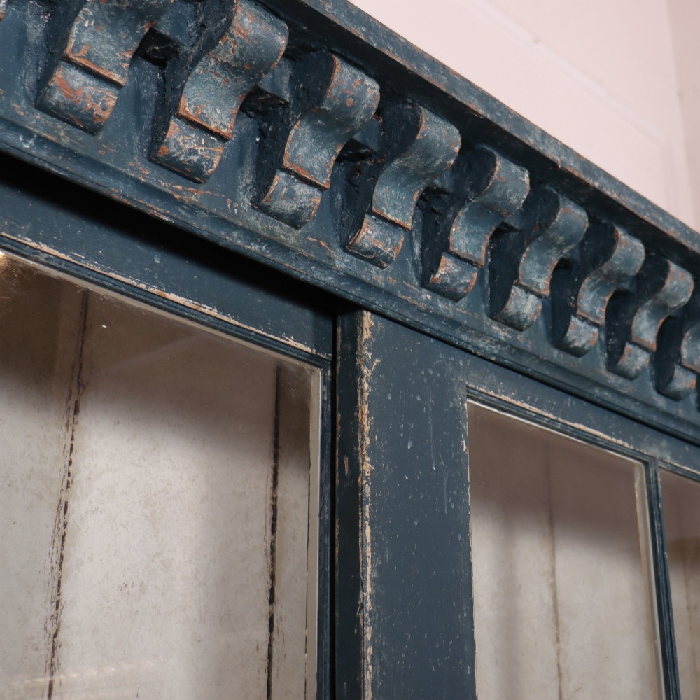 A large two-part dark blue painted timber dresser featuring a glazed upper display section with grid-paned doors and a dentil corniced top, resting on a base with three drawers and three panelled cupboard doors. View XI
