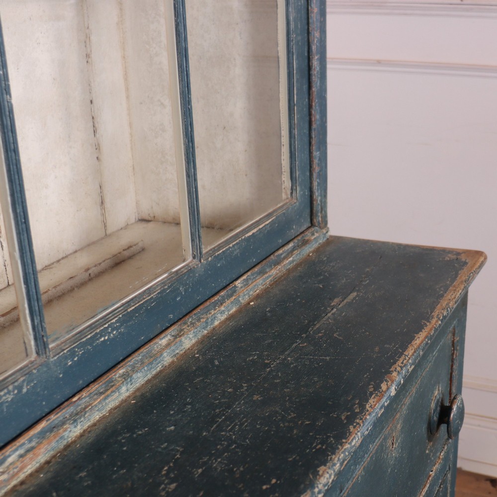 A large two-part dark blue painted timber dresser featuring a glazed upper display section with grid-paned doors and a dentil corniced top, resting on a base with three drawers and three panelled cupboard doors. View XIII