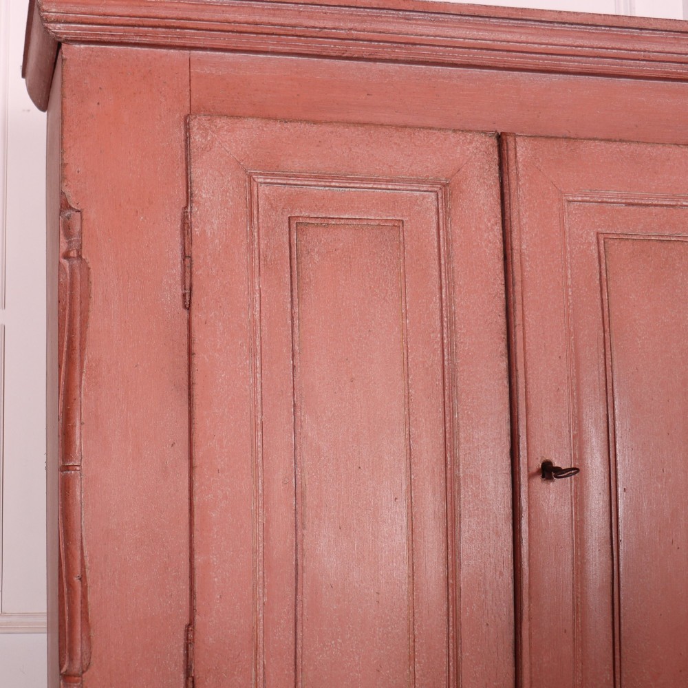 A two-piece Danish bureau bookcase featuring a terracotta red painted finish, upper panelled double cupboard doors, a cylinder roll-top desk centre, and three long drawers below. View IV