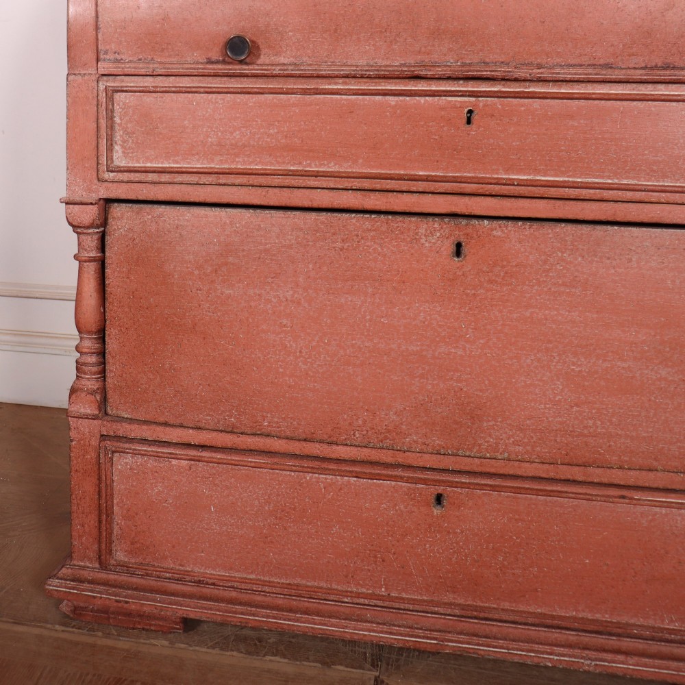 A two-piece Danish bureau bookcase featuring a terracotta red painted finish, upper panelled double cupboard doors, a cylinder roll-top desk centre, and three long drawers below. View VII