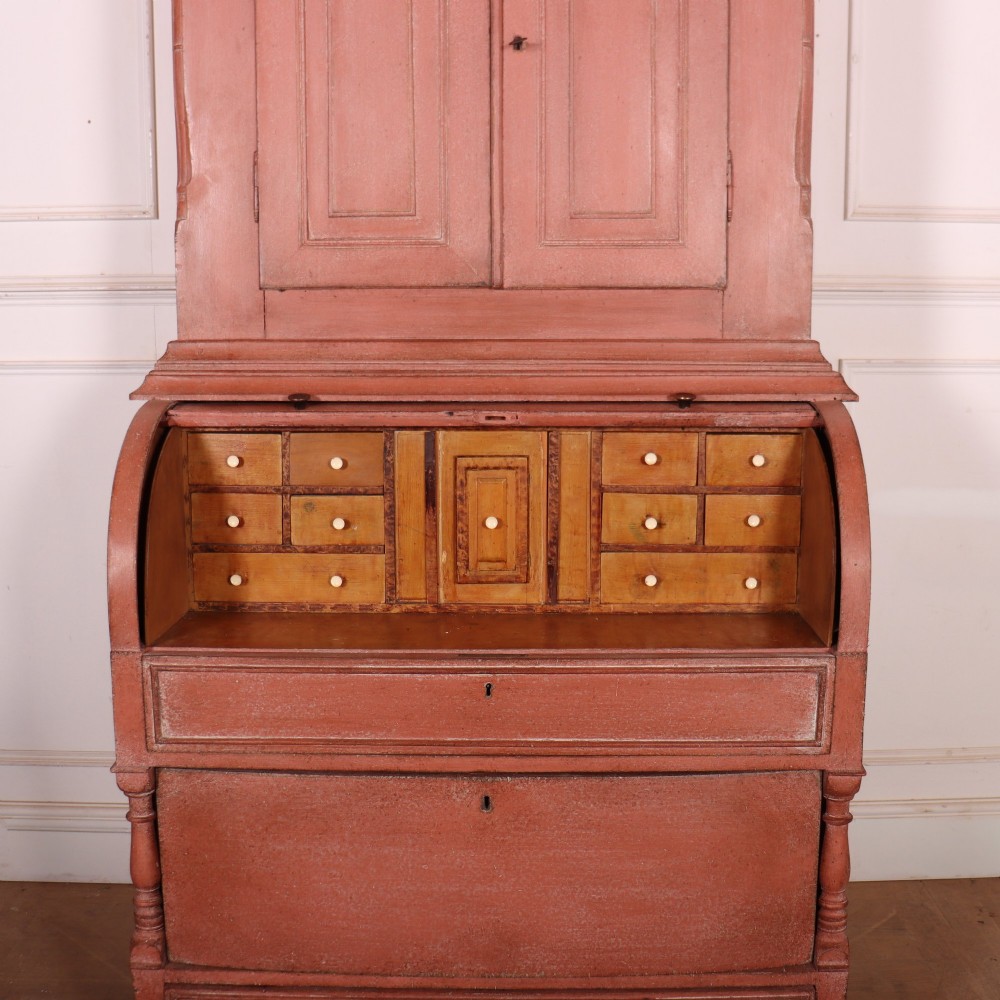 A two-piece Danish bureau bookcase featuring a terracotta red painted finish, upper panelled double cupboard doors, a cylinder roll-top desk centre, and three long drawers below. View IX