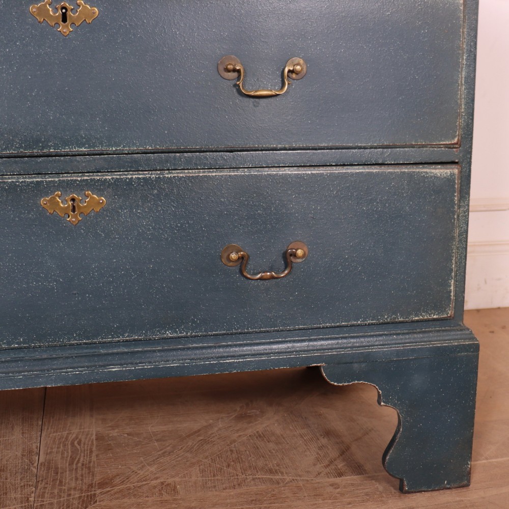 A three-drawer painted wooden chest featuring a dark blue painted finish, brass swan-neck handles, and shaped bracket feet. View IV