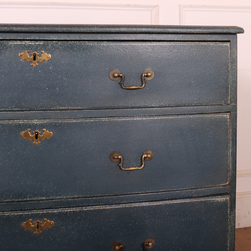 A three-drawer painted wooden chest featuring a dark blue painted finish, brass swan-neck handles, and shaped bracket feet. View V