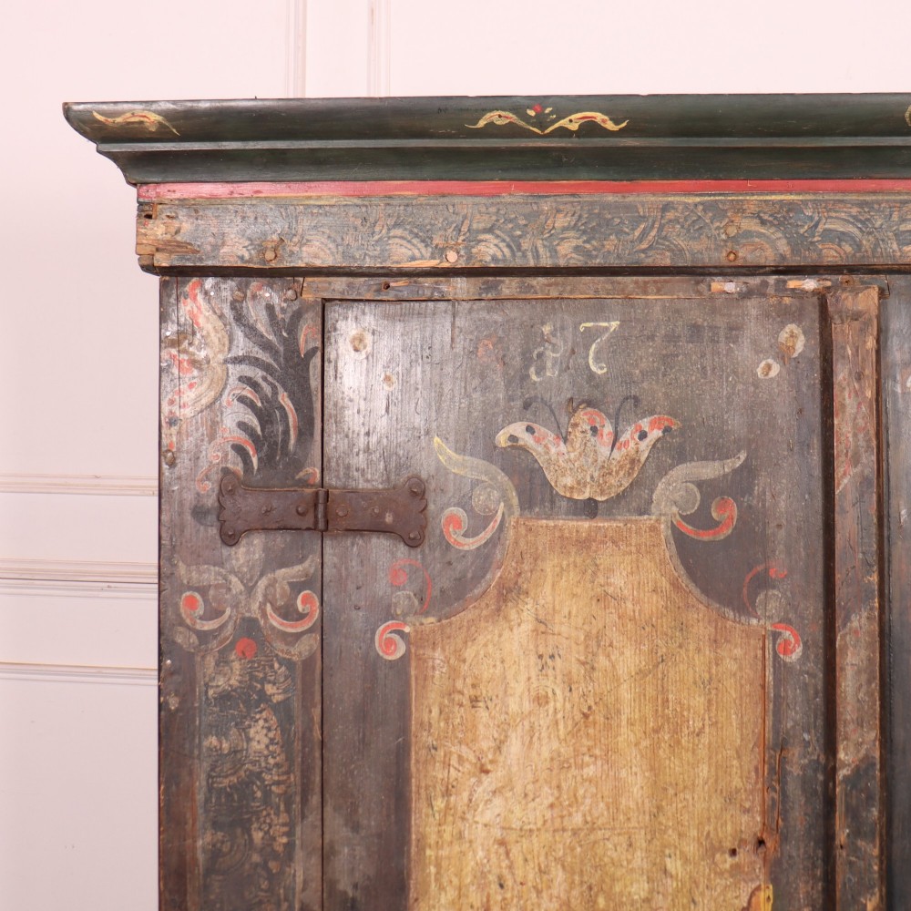 An antique two-door Austrian marriage cupboard featuring hand-painted floral motifs, central ochre panels, a scalloped base apron, and exposed iron strap hinges. View II
