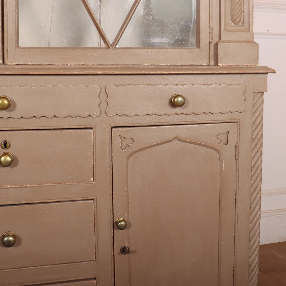 A two-part painted kitchen dresser featuring a glazed upper cabinet with geometric diamond glazing bars over a base with drawers and panelled doors. View V