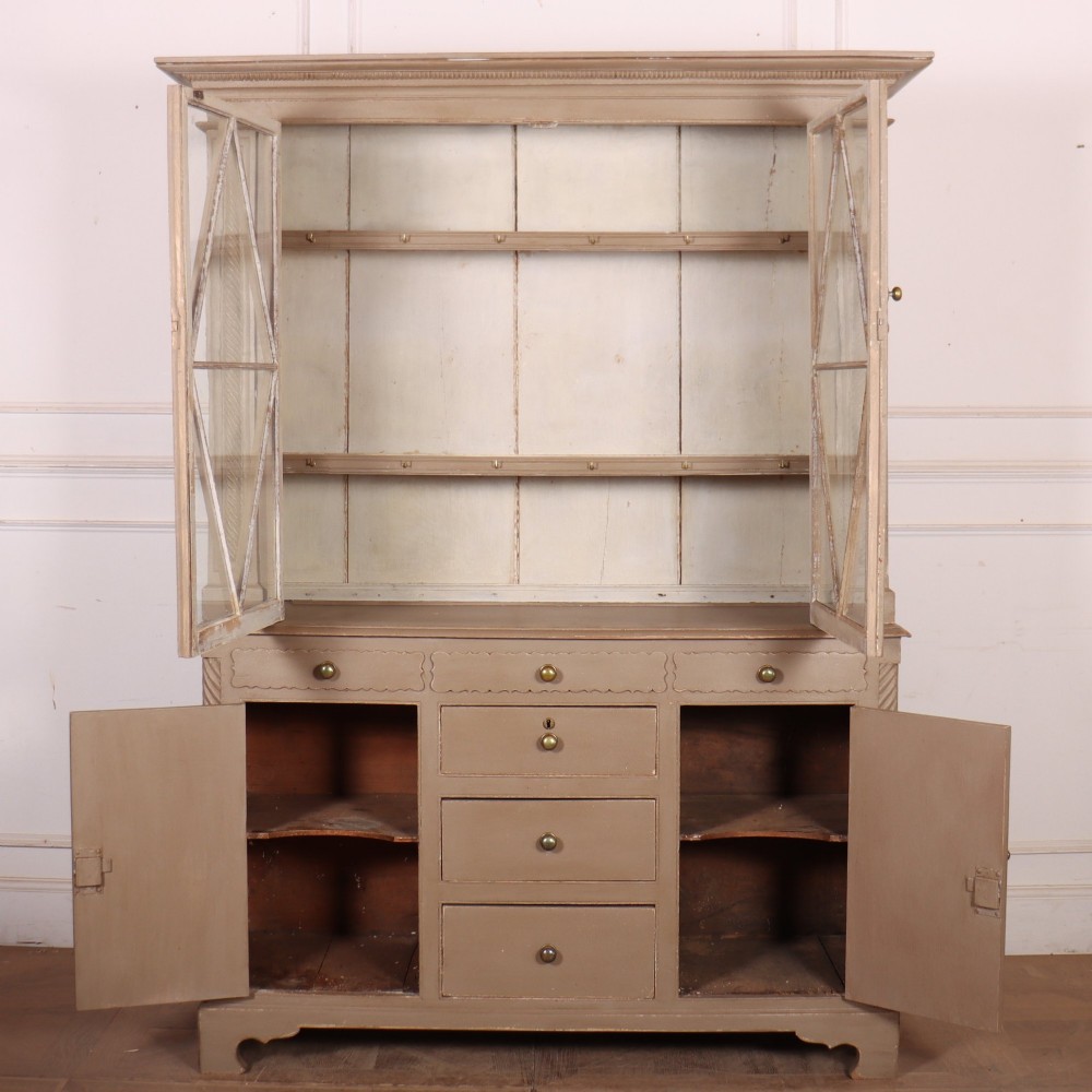 A two-part painted kitchen dresser featuring a glazed upper cabinet with geometric diamond glazing bars over a base with drawers and panelled doors. View X