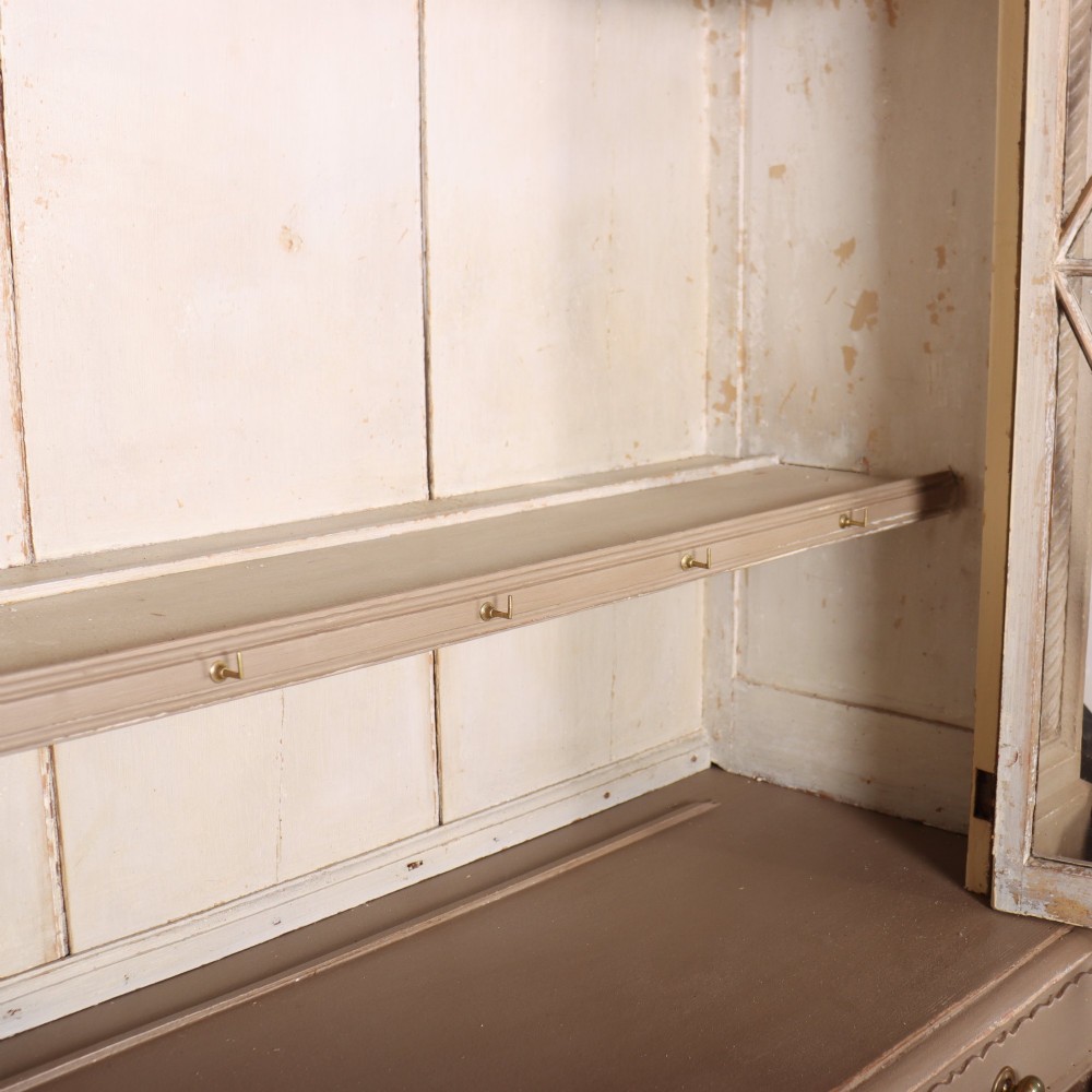 A two-part painted kitchen dresser featuring a glazed upper cabinet with geometric diamond glazing bars over a base with drawers and panelled doors. View XI