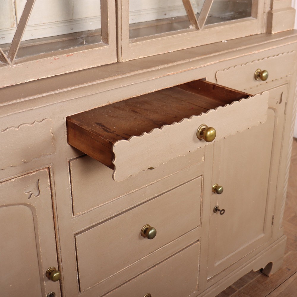 A two-part painted kitchen dresser featuring a glazed upper cabinet with geometric diamond glazing bars over a base with drawers and panelled doors. View XII