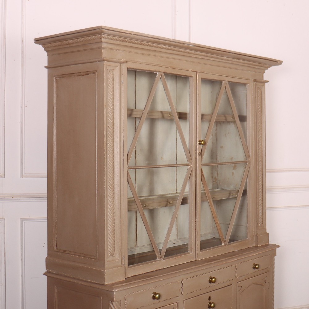 A two-part painted kitchen dresser featuring a glazed upper cabinet with geometric diamond glazing bars over a base with drawers and panelled doors. View XV