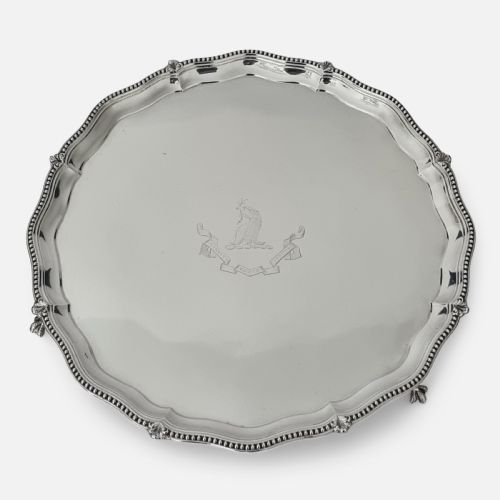 fig 2. A circular Victorian sterling silver salver with a beaded scalloped rim, small feet, and a central engraved crest.
