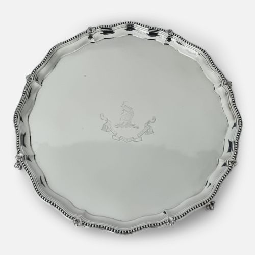 fig 3. A circular Victorian sterling silver salver with a beaded scalloped rim, small feet, and a central engraved crest.