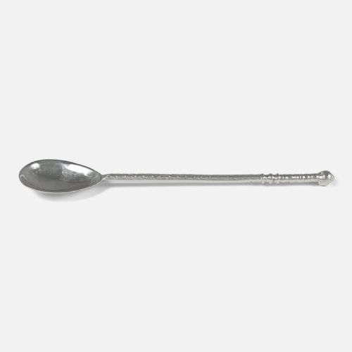 fig 2. A sterling silver spoon featuring a hand-hammered oval bowl and a long textured stem terminating in a rounded knop finial.