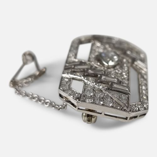 fig 3. A rectangular Art Deco platinum brooch featuring geometric openwork set with round, baguette, and a central marquise-cut diamond.