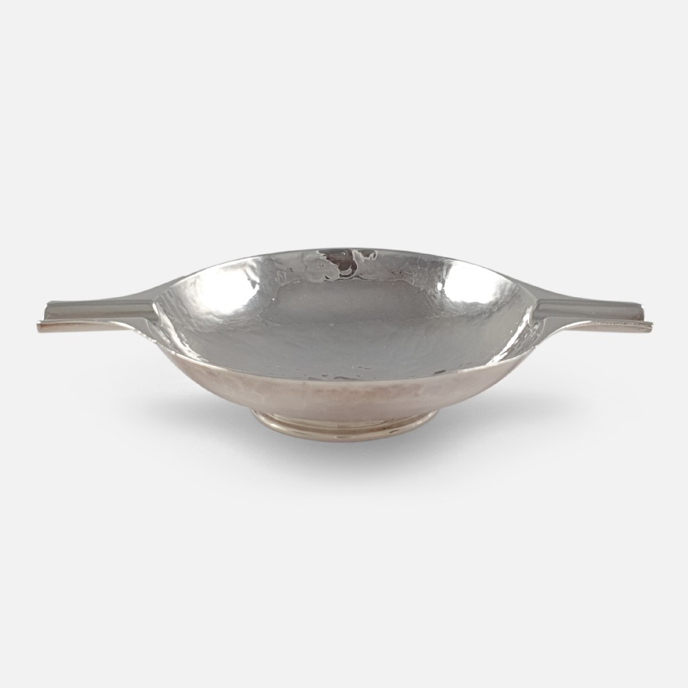 A hand-hammered sterling silver round dish featuring two extended rest arms and a raised circular foot rim.