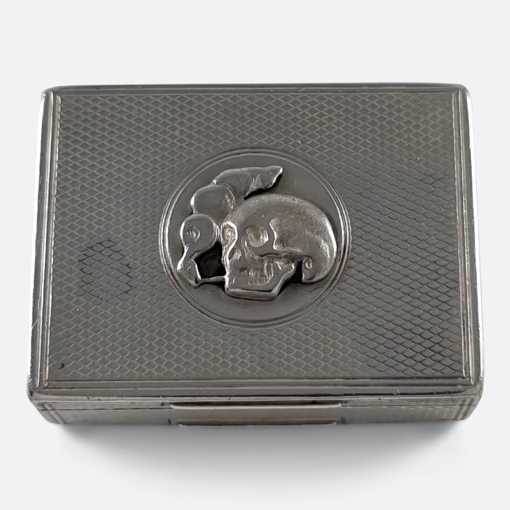 A rectangular Victorian sterling silver snuff box with engine-turned lattice engraving and a central circular relief motif of a skull.
