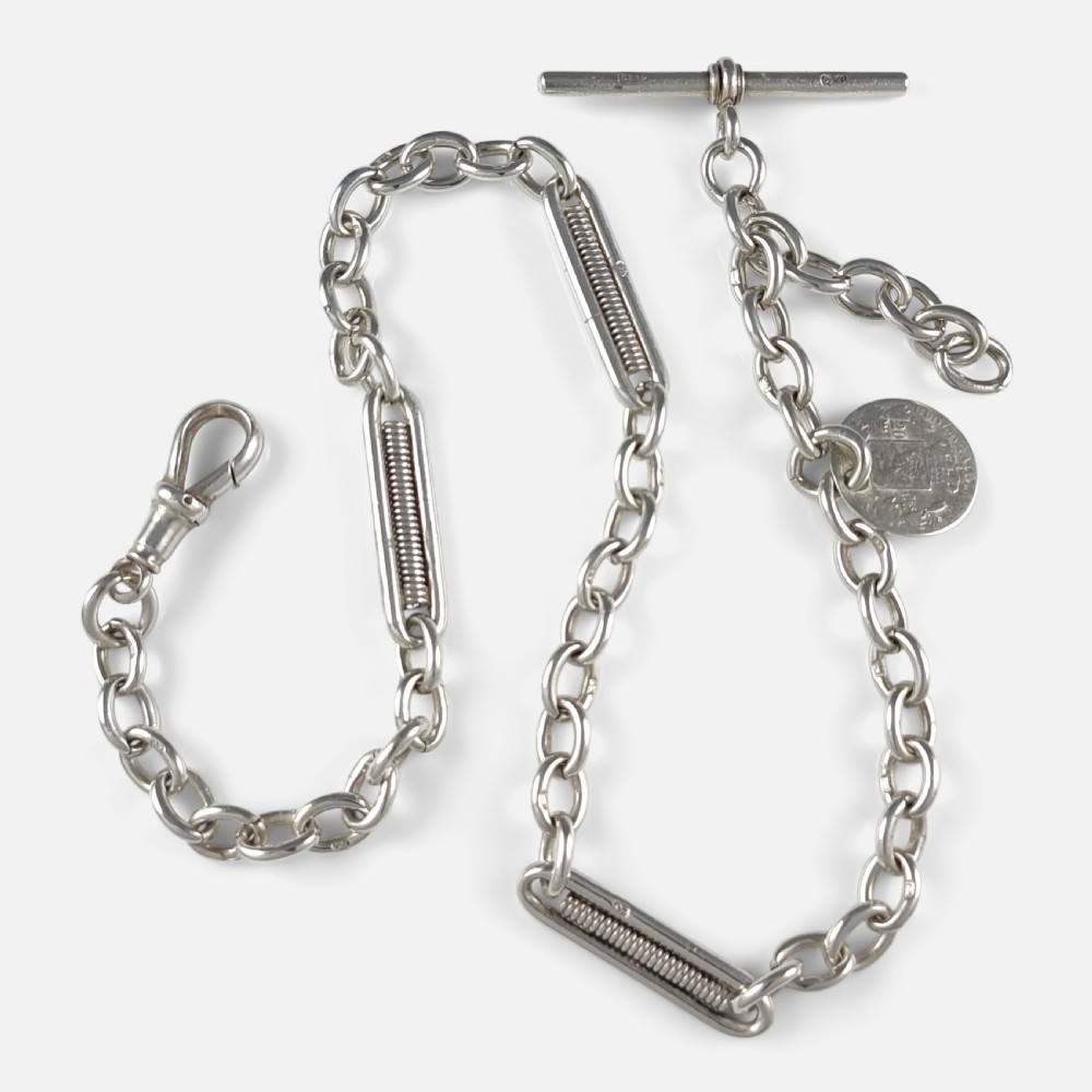 A Victorian sterling silver Albert watch chain featuring fancy coiled link sections, a T-bar, a swivel clasp, and an attached silver coin fob.