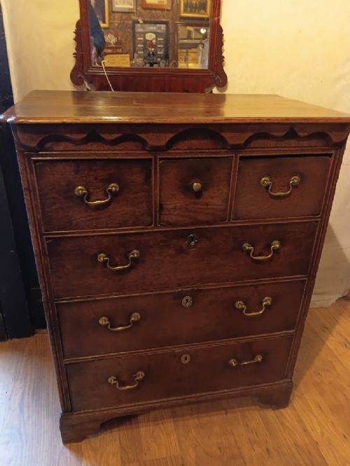 An antique brown oak chest of drawers featuring three small upper drawers over three long graduated drawers with brass drop handles. View IV