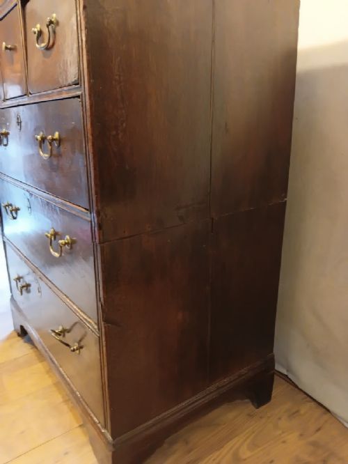 An antique brown oak chest of drawers featuring three small upper drawers over three long graduated drawers with brass drop handles. View IX