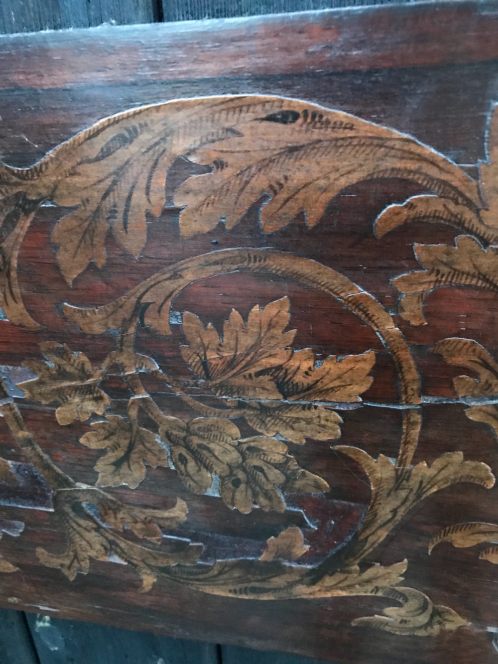 A rectangular antique wooden panel featuring detailed figurative and floral marquetry inlay work in lighter wood tones against a darker wood background. View VIII