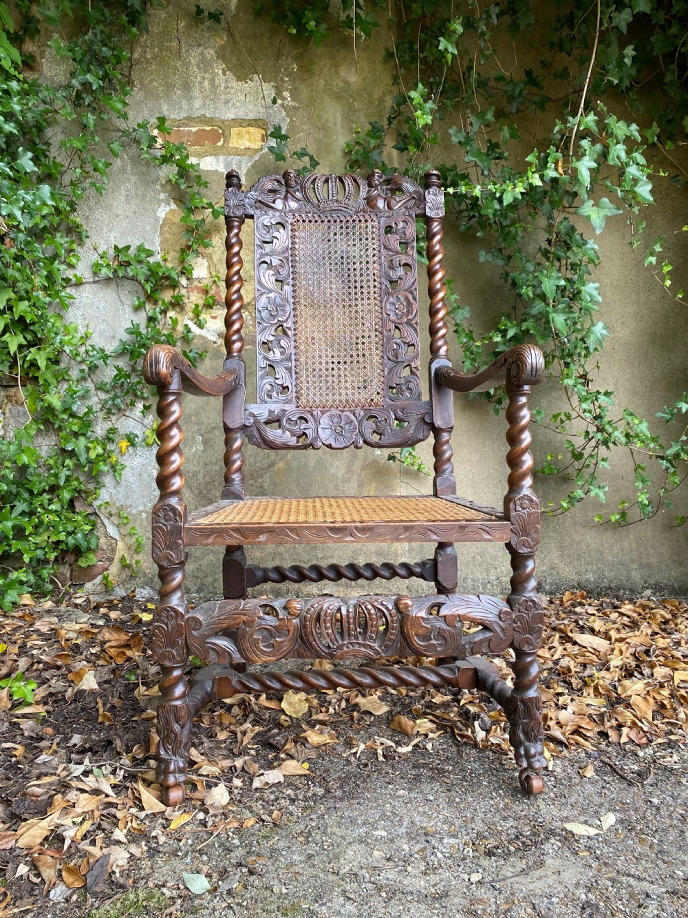 Carved Charles II walnut armchair with barley twist legs, woven cane back and seat panels, and carved crown motif.