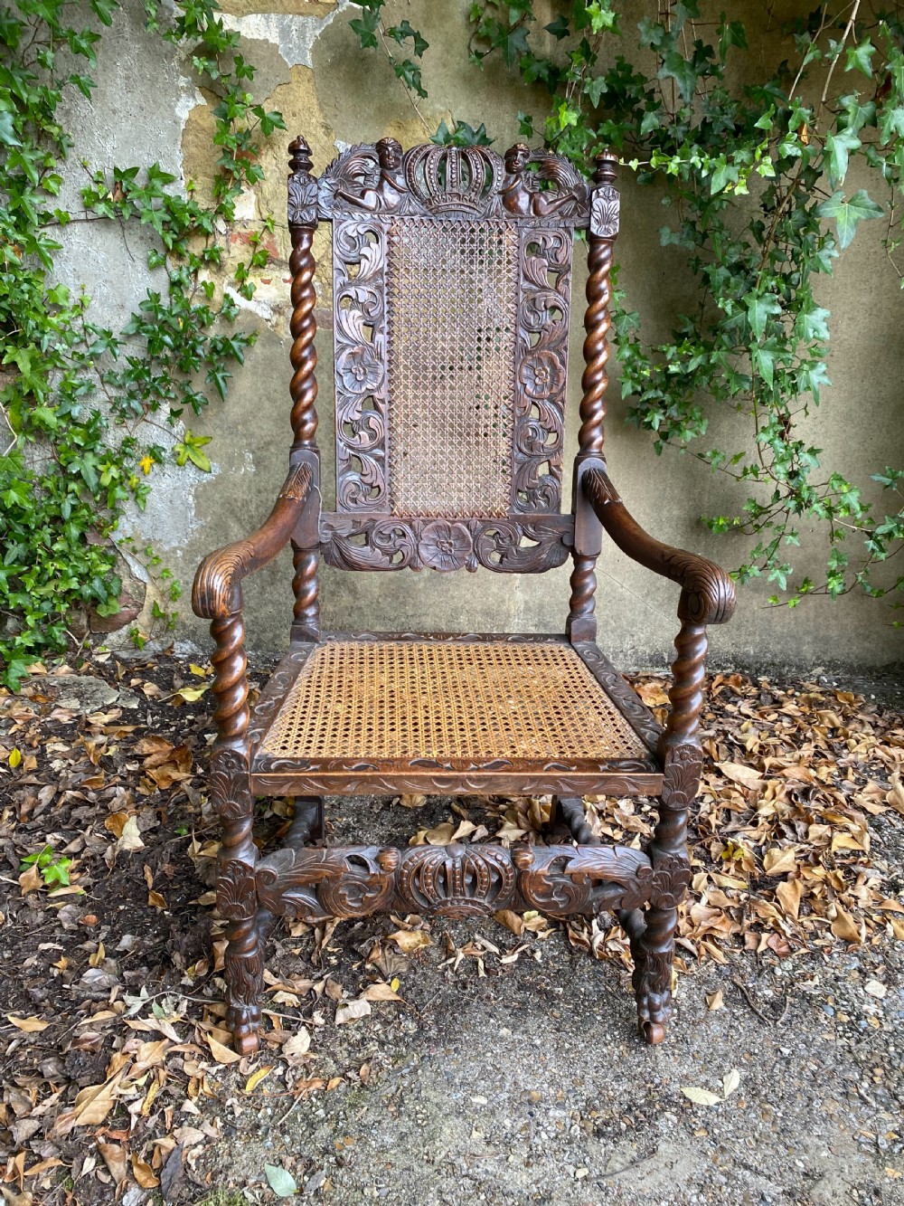 Carved Charles II walnut armchair with barley twist legs, woven cane back and seat panels, and carved crown motif. View V
