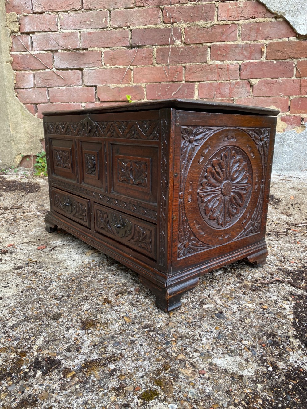 A carved dark oak Georgian coffer bach featuring a hinged lid, relief-carved floral panels, two lower drawers, and bracket feet. View VIII