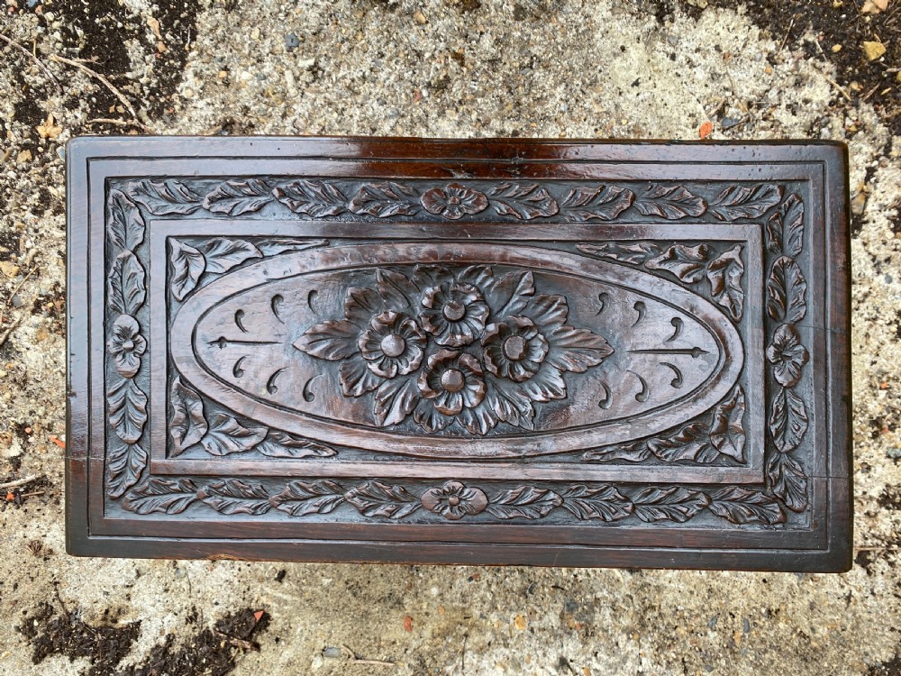 A carved dark oak Georgian coffer bach featuring a hinged lid, relief-carved floral panels, two lower drawers, and bracket feet. View XII