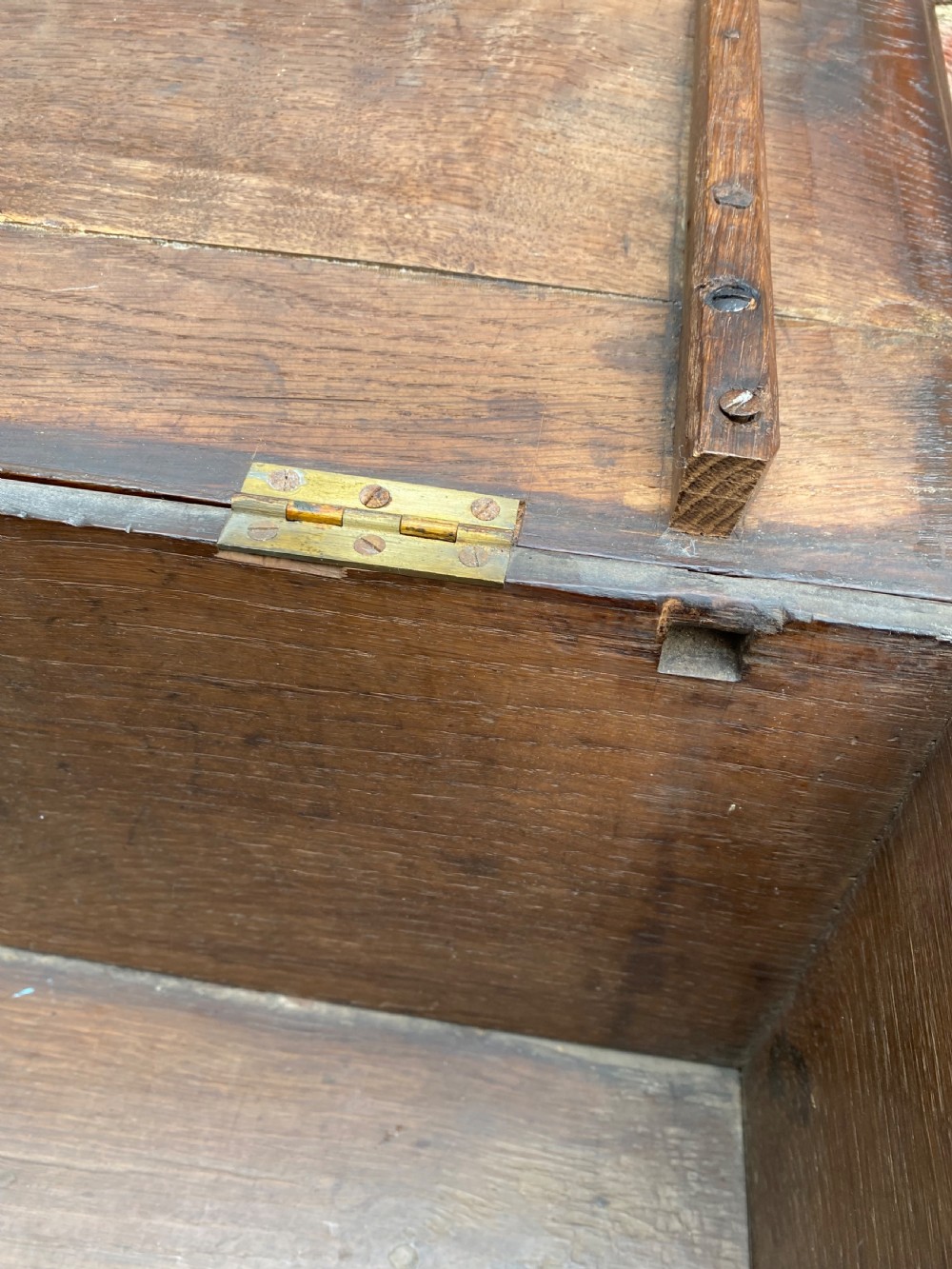 A carved dark oak Georgian coffer bach featuring a hinged lid, relief-carved floral panels, two lower drawers, and bracket feet. View XVII