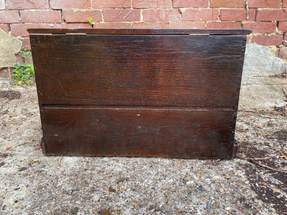 A carved dark oak Georgian coffer bach featuring a hinged lid, relief-carved floral panels, two lower drawers, and bracket feet. View XVIII