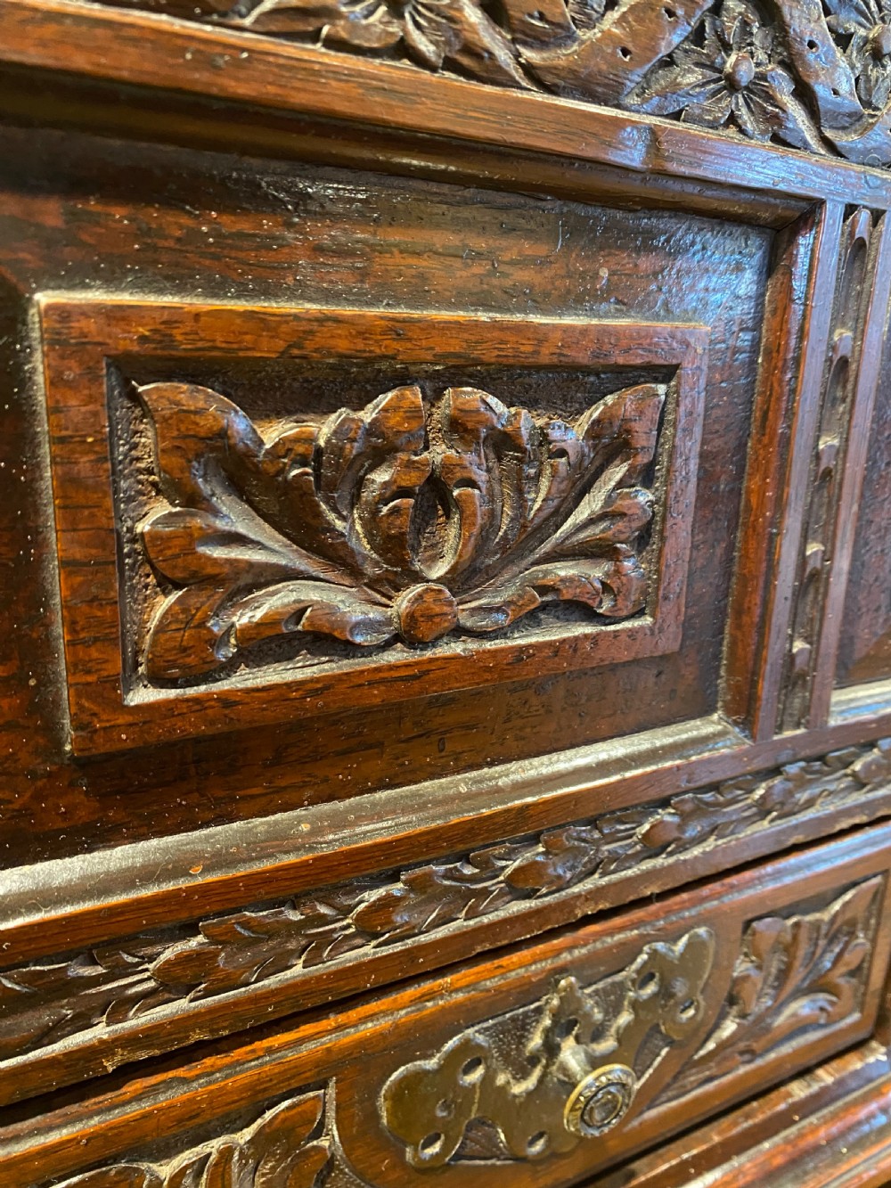 A carved dark oak Georgian coffer bach featuring a hinged lid, relief-carved floral panels, two lower drawers, and bracket feet. View XX