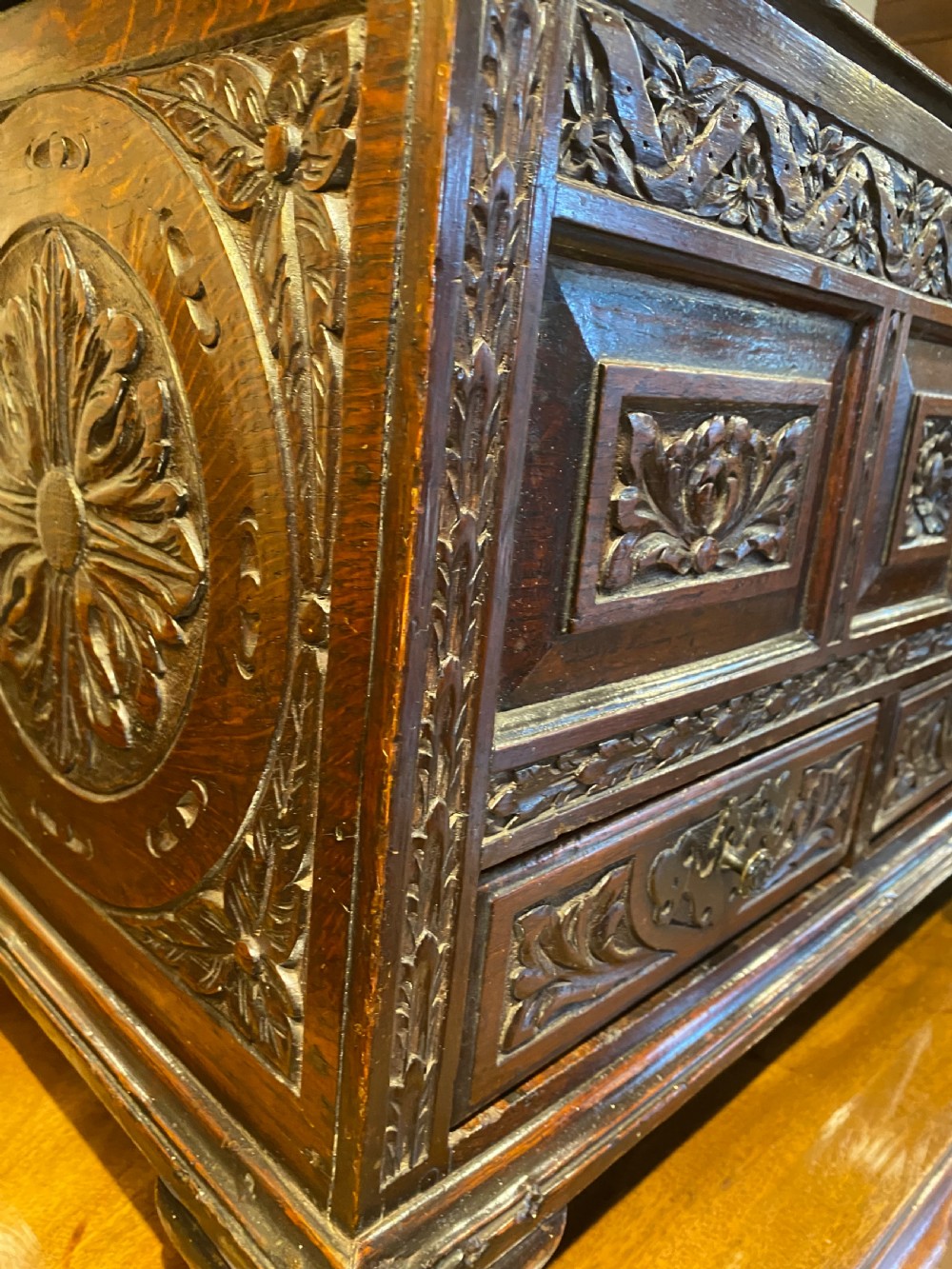A carved dark oak Georgian coffer bach featuring a hinged lid, relief-carved floral panels, two lower drawers, and bracket feet. View XXI