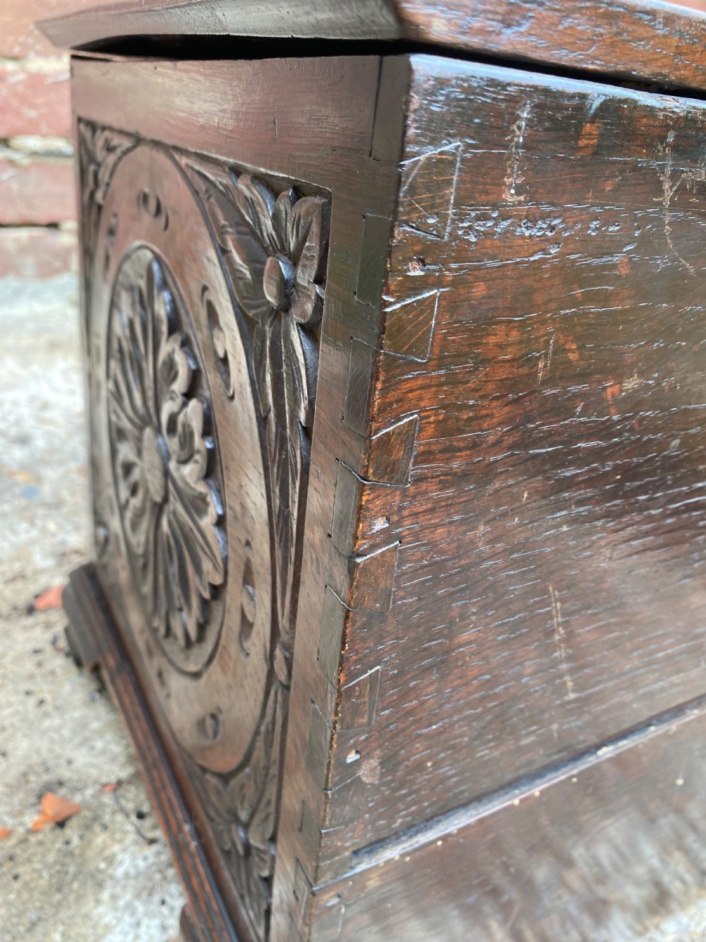 A carved dark oak Georgian coffer bach featuring a hinged lid, relief-carved floral panels, two lower drawers, and bracket feet. View XXII
