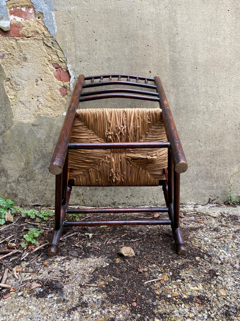 A dark wood Arts and Crafts Sussex armchair featuring a turned spindle backrest, curved armrests, and a woven rush seat. View XIV