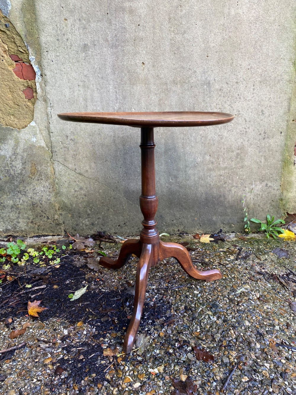 A Georgian mahogany circular side table featuring a dished top, a turned central column, and three tripod cabriole legs. View III
