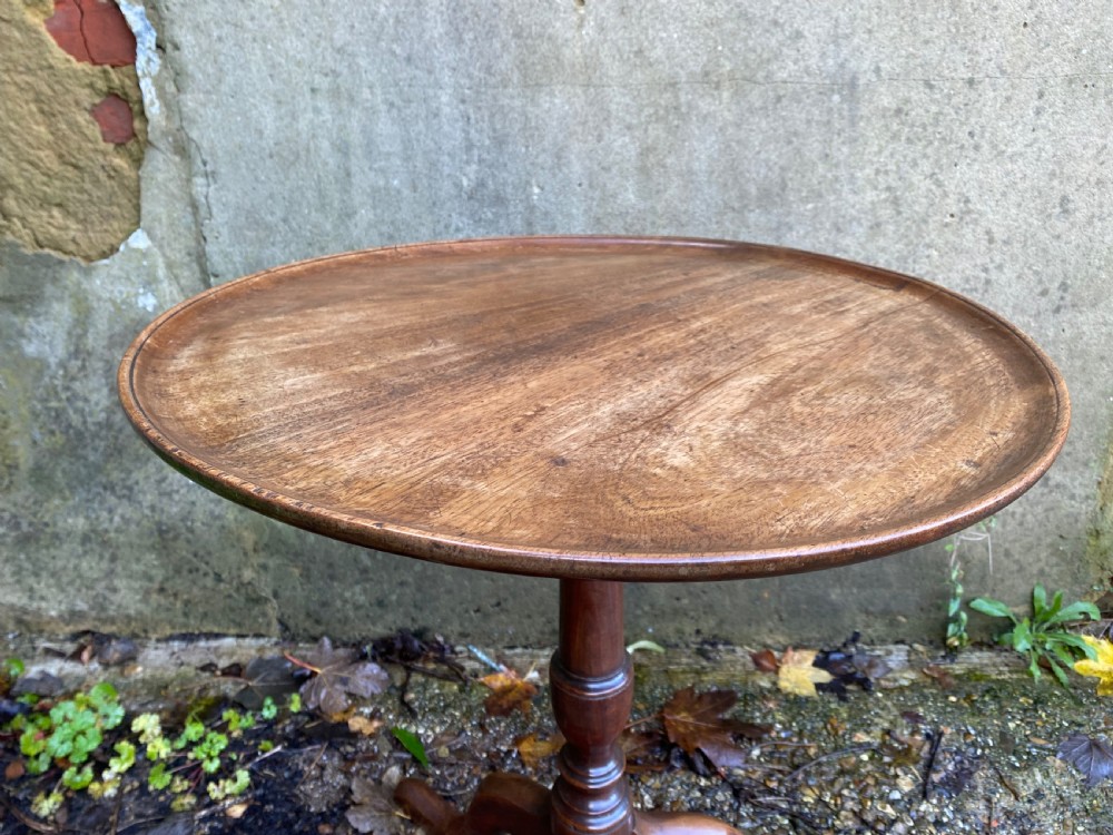 A Georgian mahogany circular side table featuring a dished top, a turned central column, and three tripod cabriole legs. View V