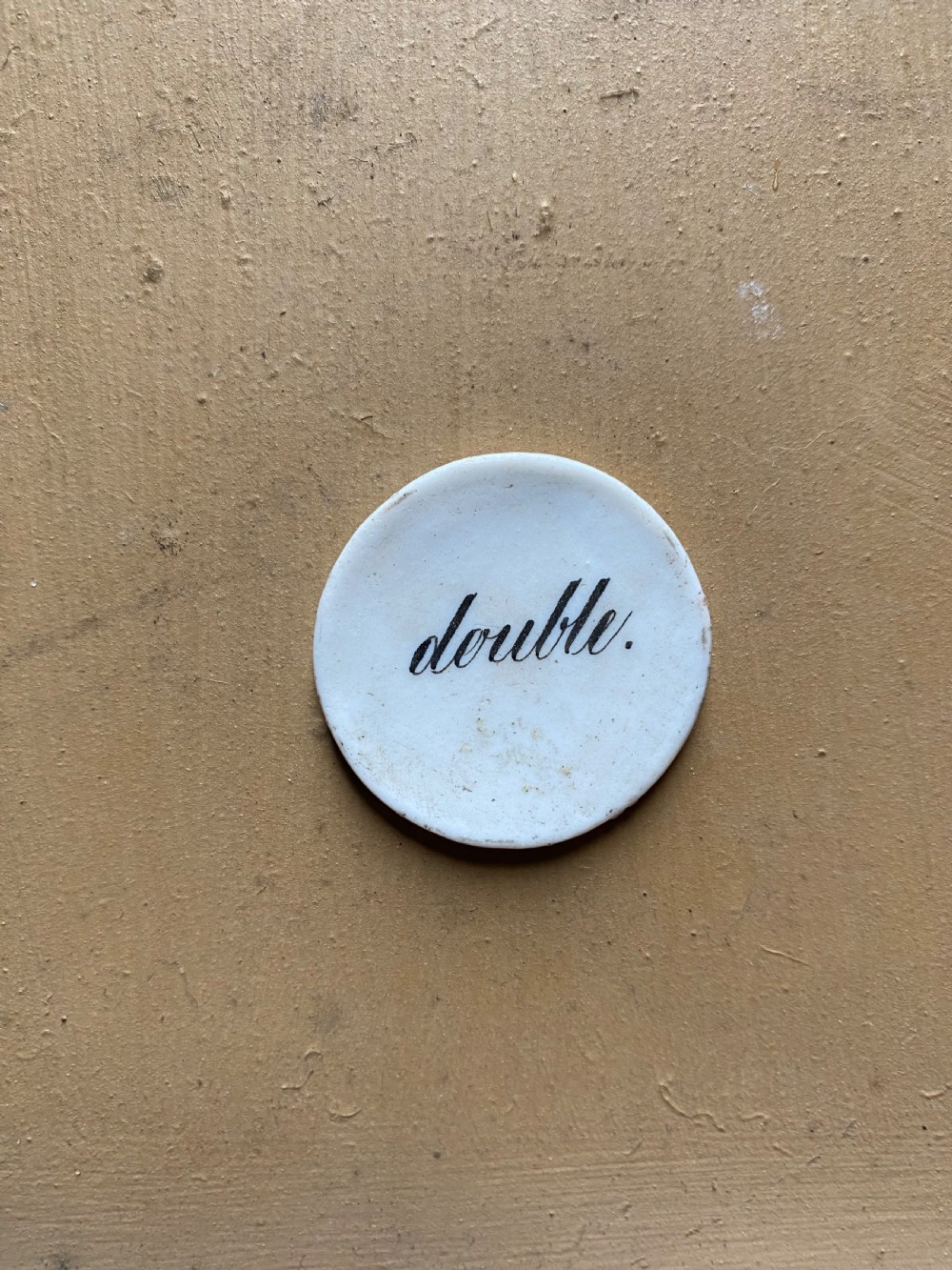 A set of six circular white porcelain gaming tokens decorated with hand-painted playing card king figures and cursive script lettering. View X