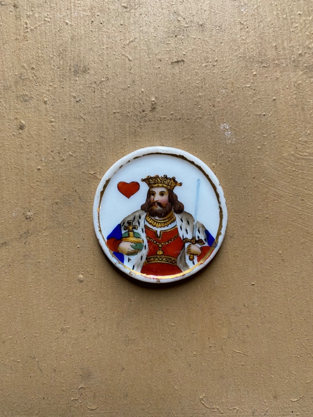 A set of six circular white porcelain gaming tokens decorated with hand-painted playing card king figures and cursive script lettering. View XI