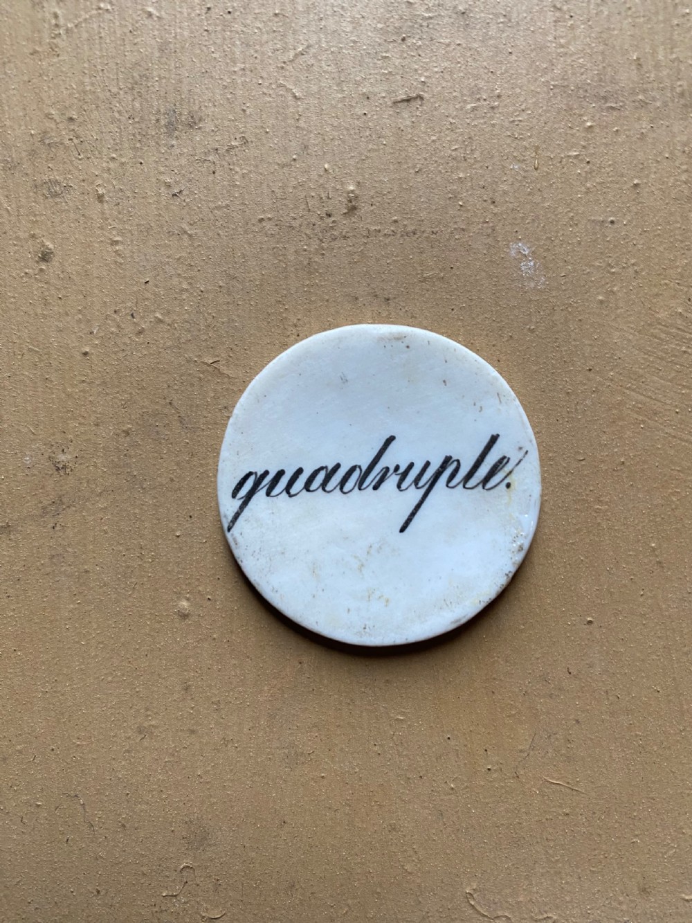 A set of six circular white porcelain gaming tokens decorated with hand-painted playing card king figures and cursive script lettering. View XII