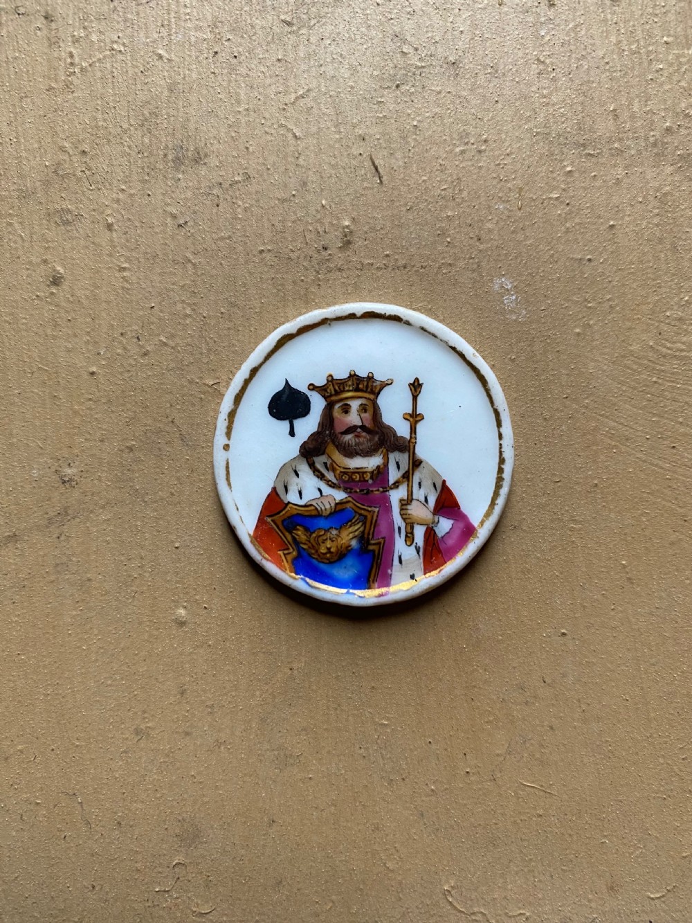 A set of six circular white porcelain gaming tokens decorated with hand-painted playing card king figures and cursive script lettering. View XIII
