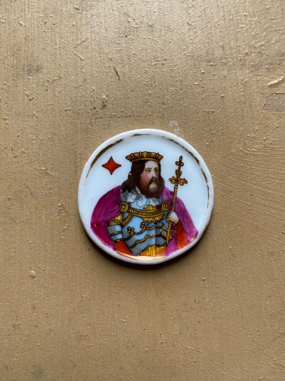 A set of six circular white porcelain gaming tokens decorated with hand-painted playing card king figures and cursive script lettering. View XV
