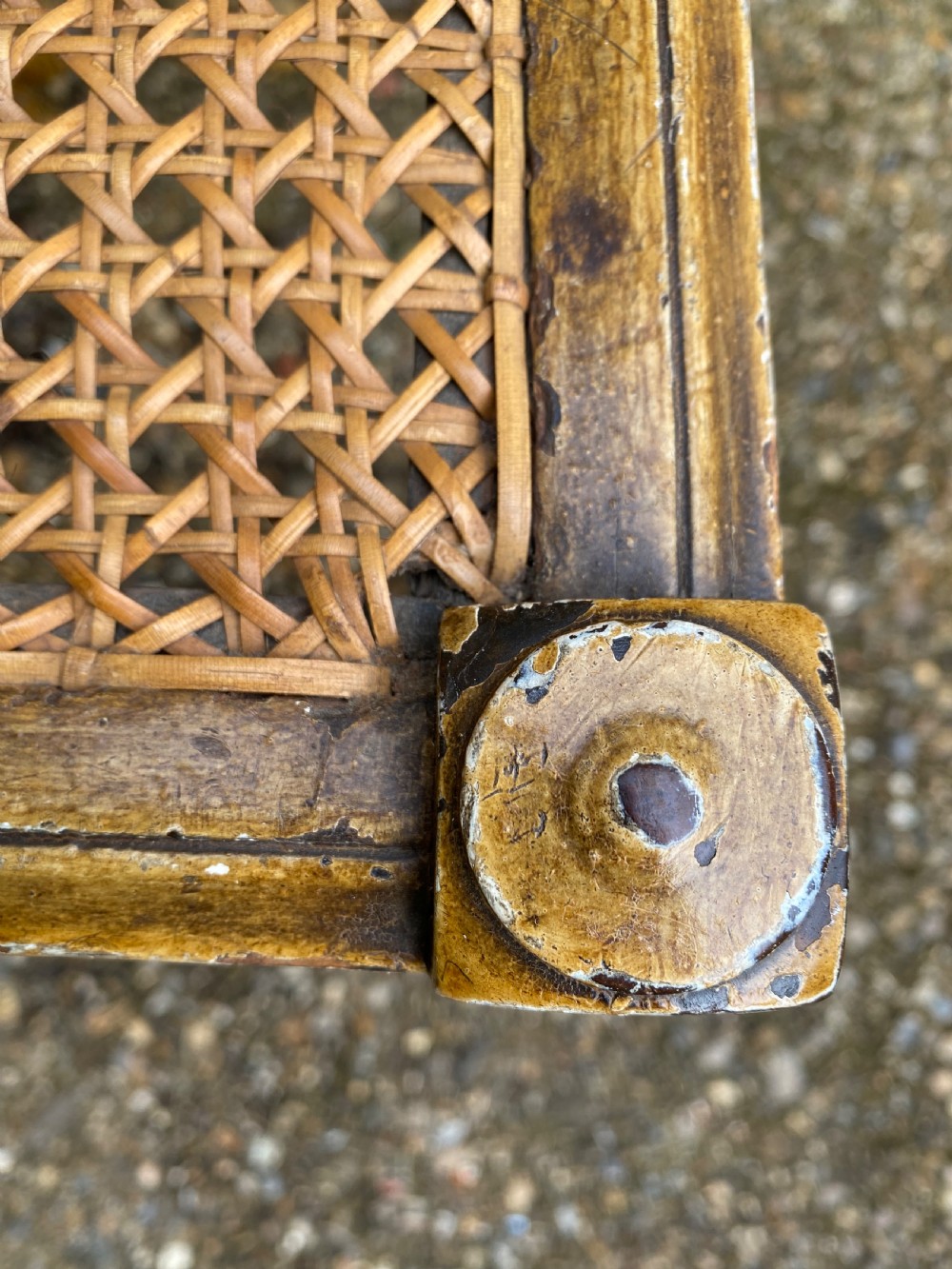 A rectangular wooden stool featuring turned bobbin legs, horizontal stretchers, and a woven cane seat panel with a distressed warm brown finish. View XVIII