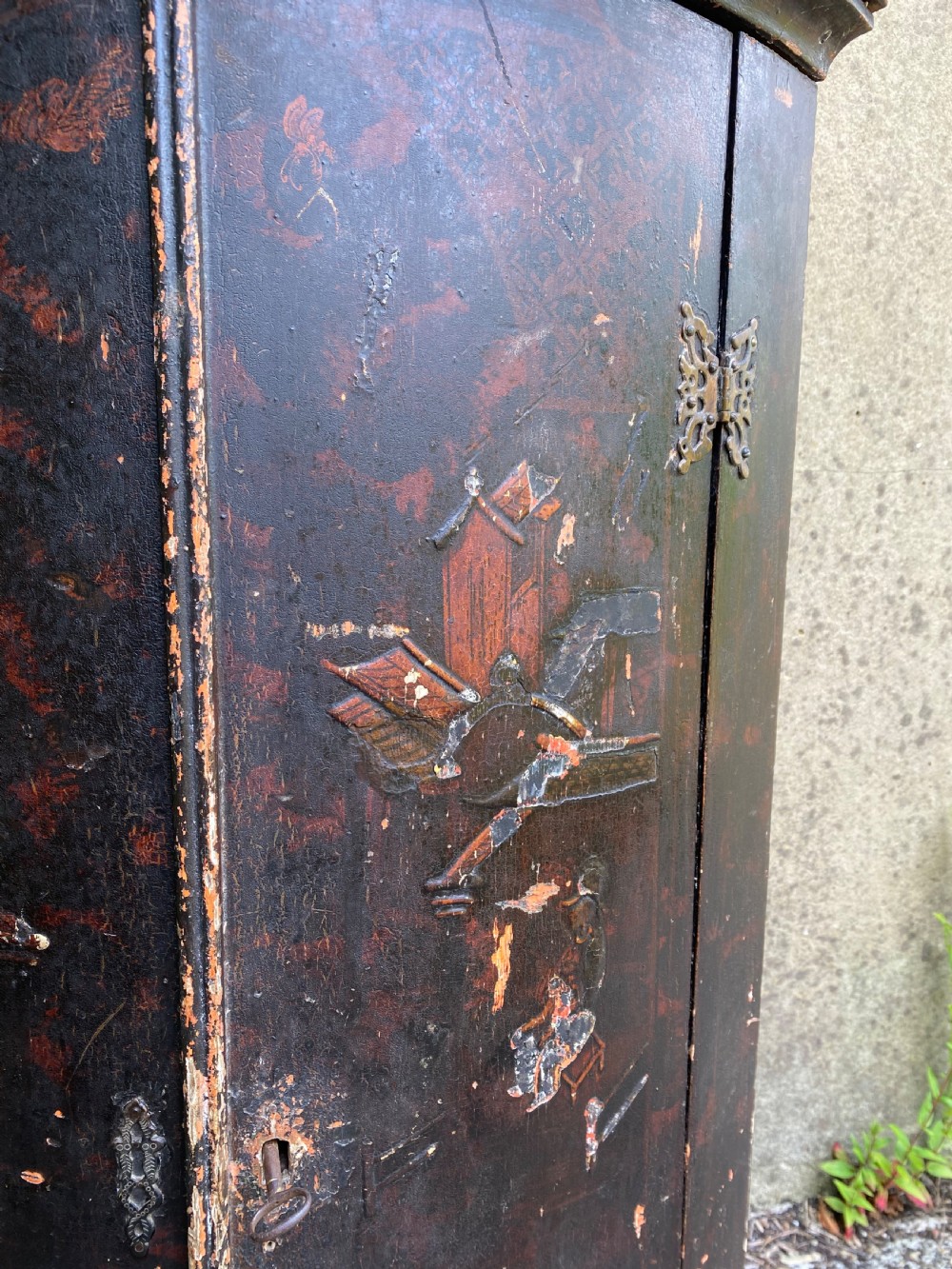 A dark lacquered Georgian corner cupboard featuring hand-painted Chinoiserie figures, architectural motifs, and brass butterfly hinges. View V