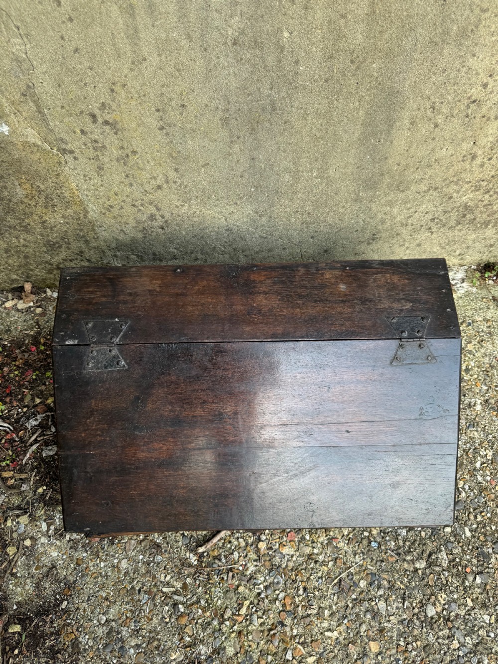 A small dark oak coffer featuring a carved top frieze, a three-panel front, and a central iron escutcheon. View II
